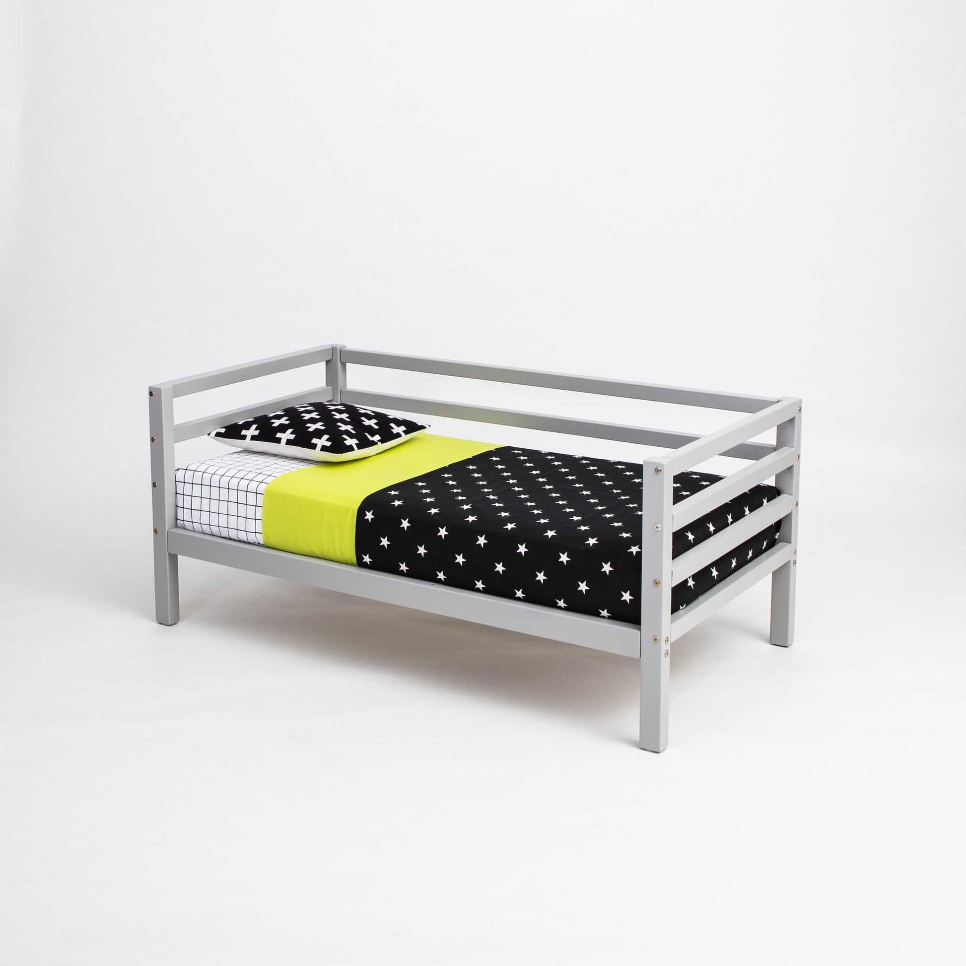 A Sweet Home From Wood 2-in-1 transformable kids' bed with a 3-sided horizontal rail, featuring a grey toddler bed and a black and yellow polka dot blanket.