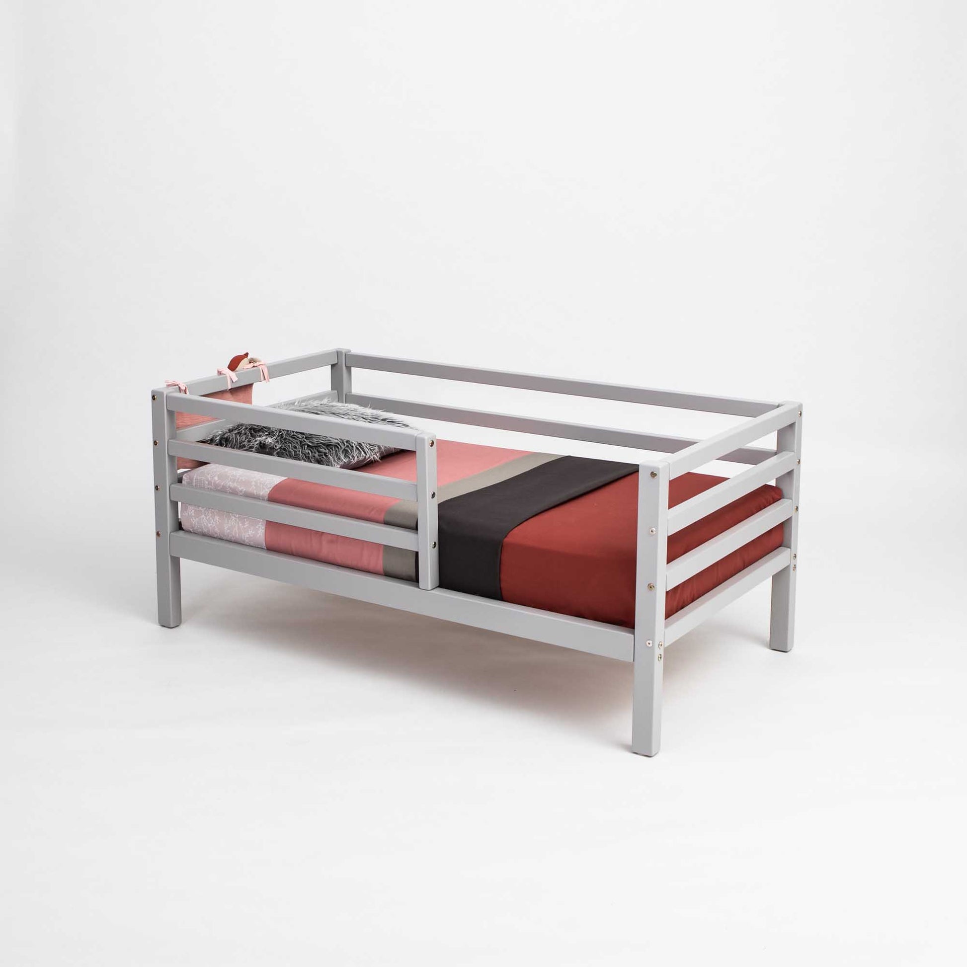 A Sweet Home From Wood 2-in-1 transformable kids' bed with a horizontal rail fence and a red and black sheet.