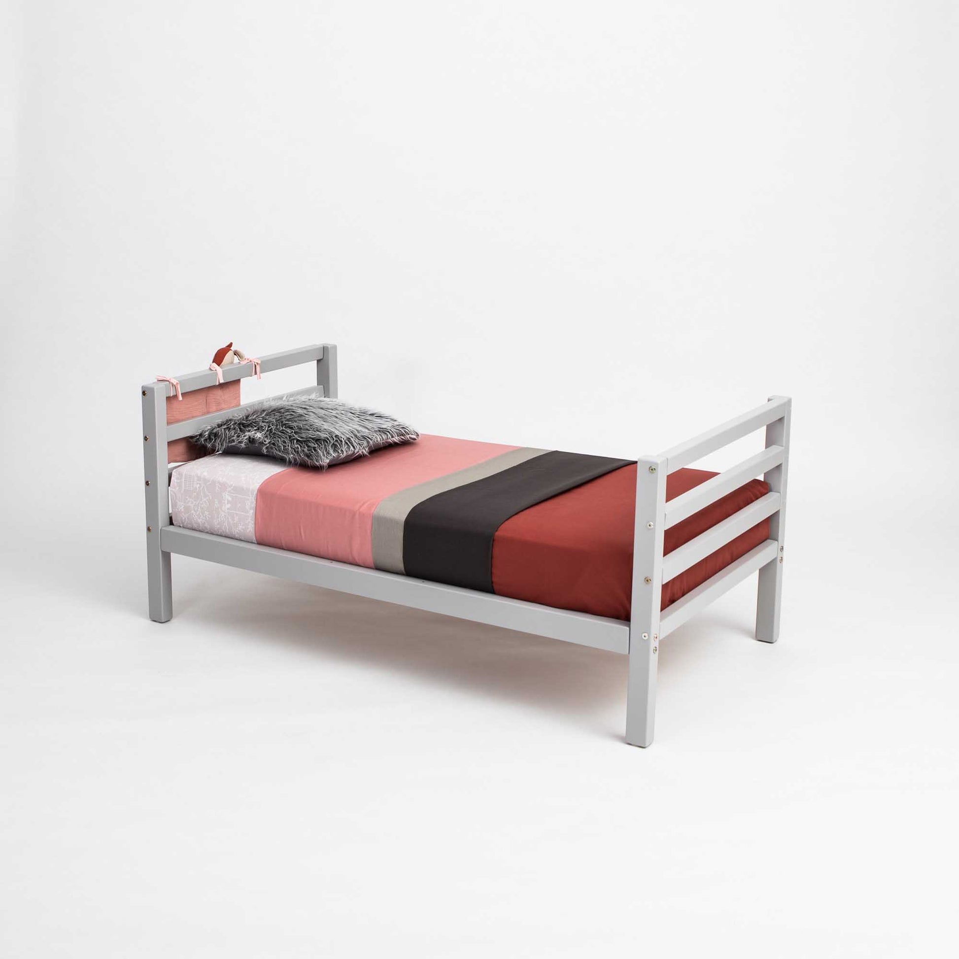 A long-lasting Sweet Home From Wood 2-in-1 kid's bed with a gray frame and red and black bedding that grows with the child.