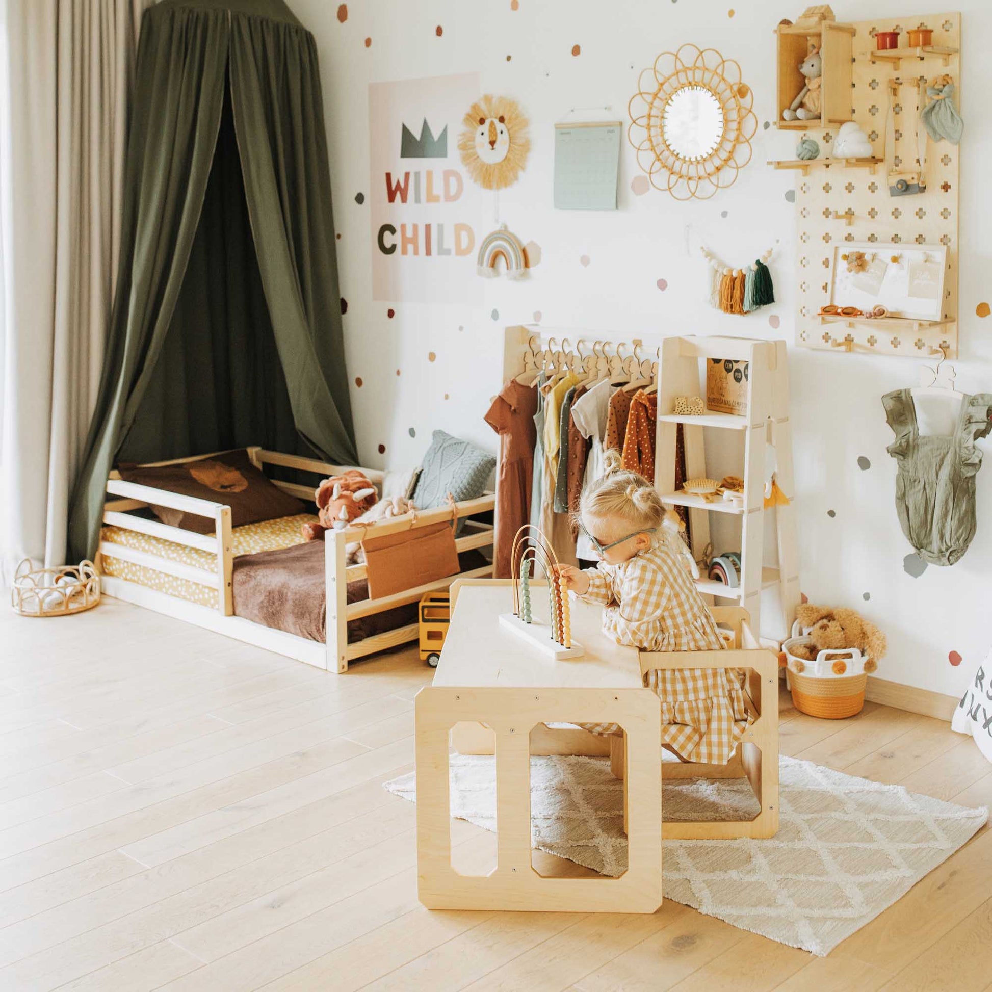 A Sweet Home From Wood Montessori weaning table and chair set child's room with a wooden desk and polka dot walls.