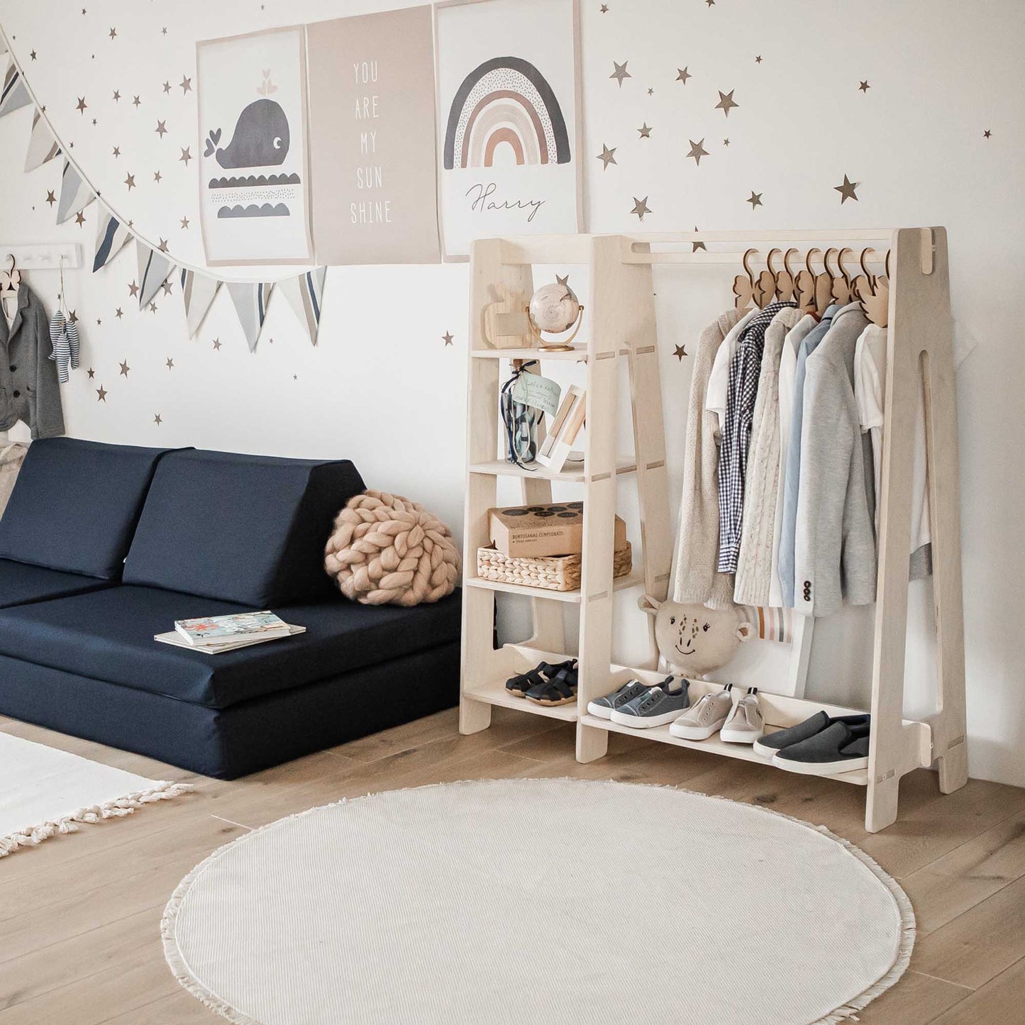 A child's room with a white couch, white walls, and stars on the wall. Additionally, it features a Sweet Home From Wood children's wardrobe for organizing kids' clothing.