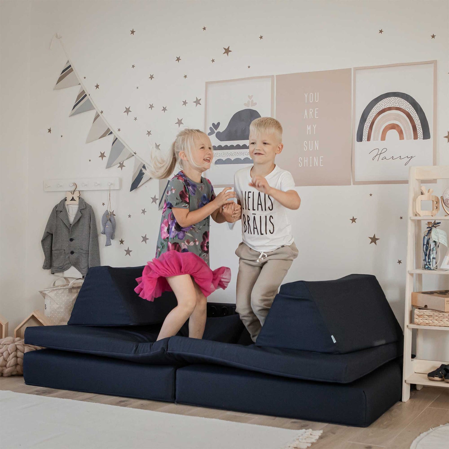 Two children playing on a couch in a child's room.