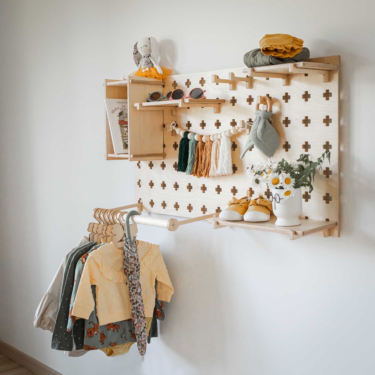 A child's room with open storage shelves for Sweet HOME from wood Pegboards with Clothes Hanger hanging on a wall.