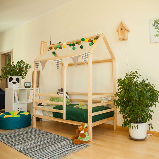 A child's room with a wooden house bed on legs with a fence adorned with a teddy bear.