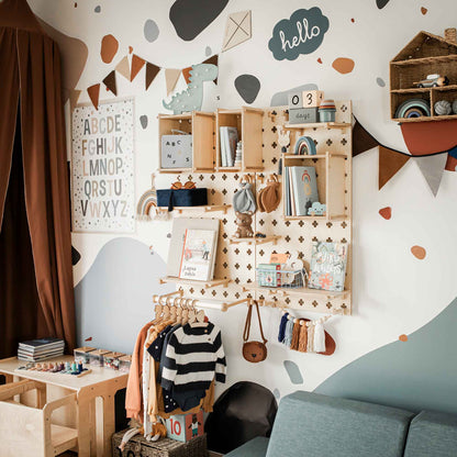 A neatly organized children's playroom showcases customizable layouts, with a Large Pegboard Shelf with Clothes Hanger holding educational and decorative items, hanging clothes, a wall-mounted alphabet chart, and playful wall decals.