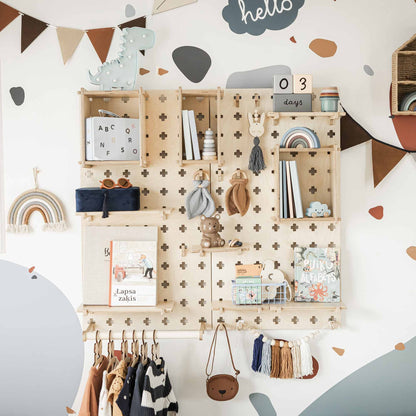 A neatly organized children's wall features a Large Pegboard Shelf with Clothes Hanger, showcasing floating shelves adorned with various toys, books, and decorations. Among the items on display are a stuffed teddy bear, a rainbow mobile, and hanging clothes. This customizable layout also includes an organizer with a calendar displaying "03 days" on the top shelf.