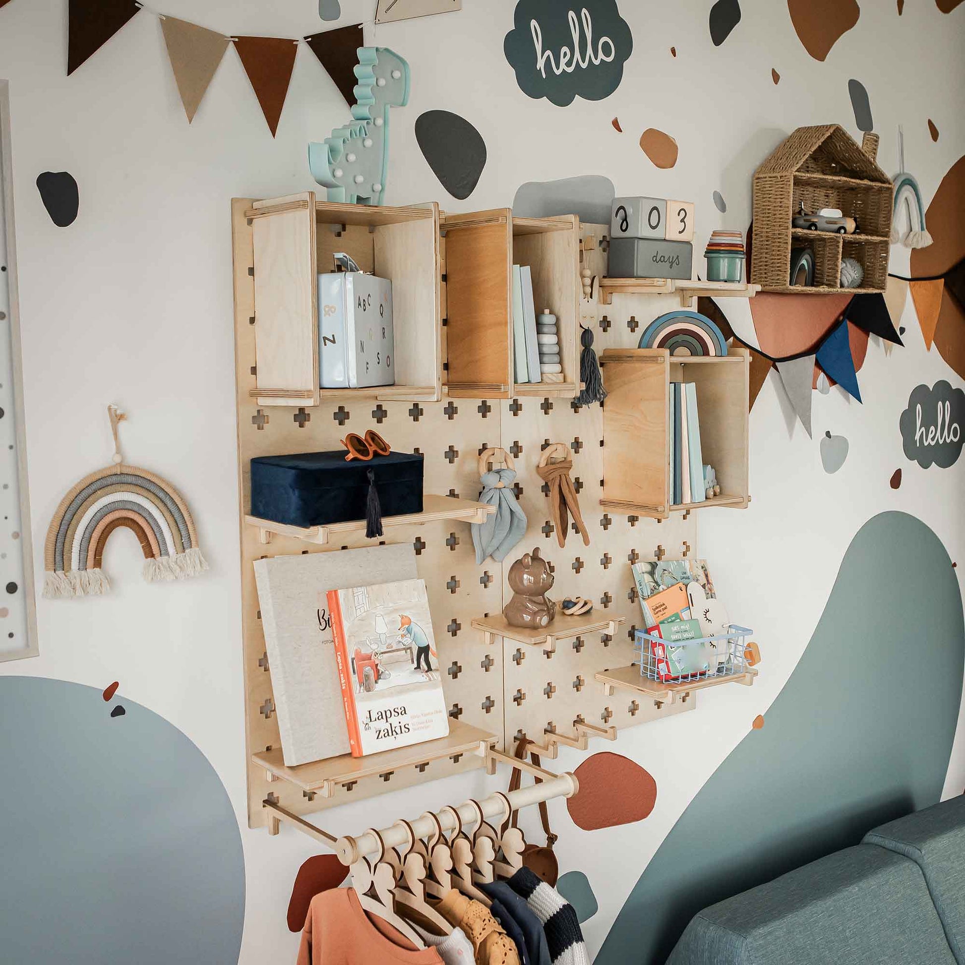 A children's room wall is adorned with a Large Pegboard Shelf with Clothing Rack, used to display books, toys, and decorations. Colorful wall art and a hanging rainbow decor add vibrancy, while the pegboard's customizable layout efficiently organizes children's clothes and keeps the room tidy and fun.