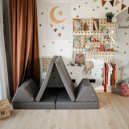 Children's playroom with a foldable foam couch set up as a tent, a Large Pegboard Shelf with Clothing Rack holding various toys and decorations, an organizer for keeping things tidy, and a colorful dotted accent wall.