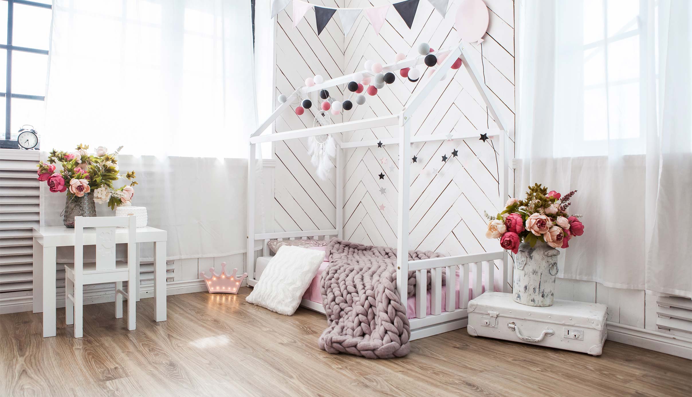 A girl's room with a white bed and pink and white decorations.
