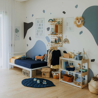 A neatly organized children's bedroom with a Kids' bed on legs featuring a horizontal rail headboard and a sturdy frame made of solid pine wood. The room includes toys, a blue and white color palette, various storage solutions, and walls adorned with alphabet and motivational prints.