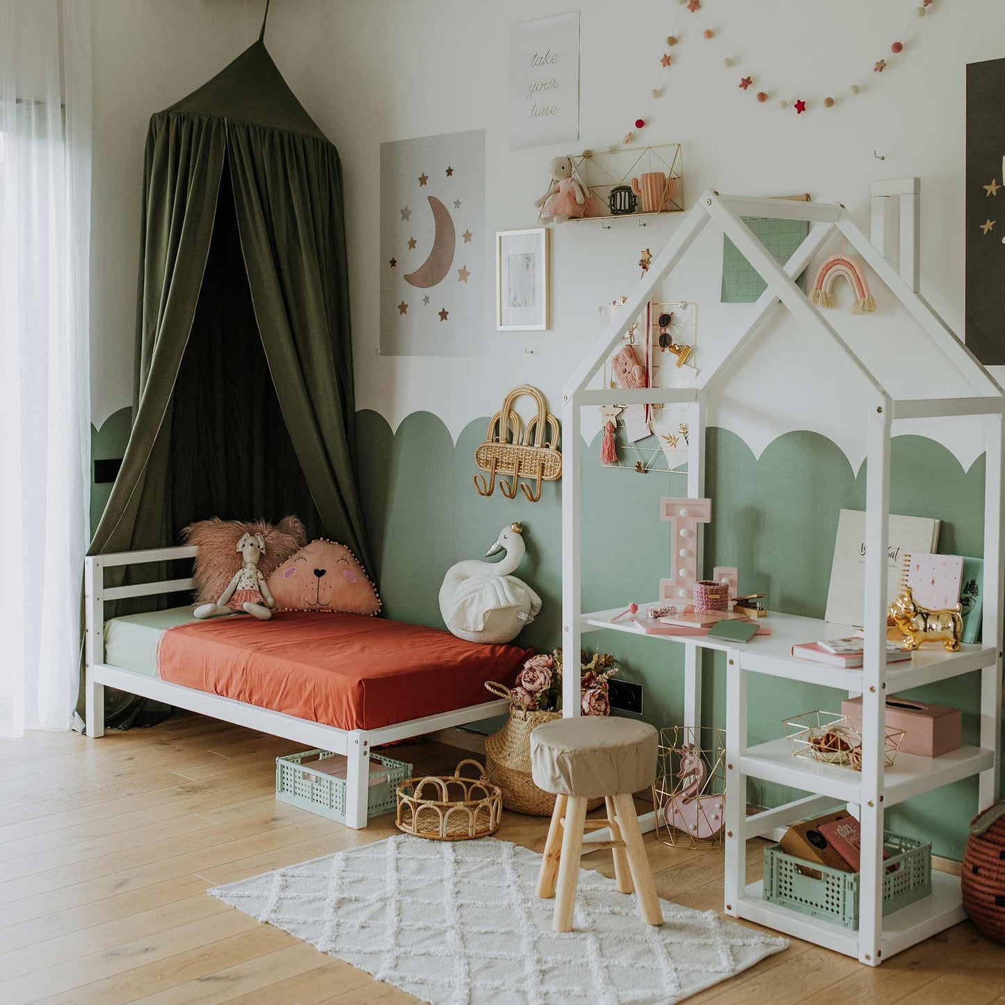 A cozy children's room with a Montessori-inspired Kids' bed on legs featuring a horizontal rail headboard, crafted from solid pine, adorned with toys, a small desk, wall decorations, and designed in a green and white color scheme.