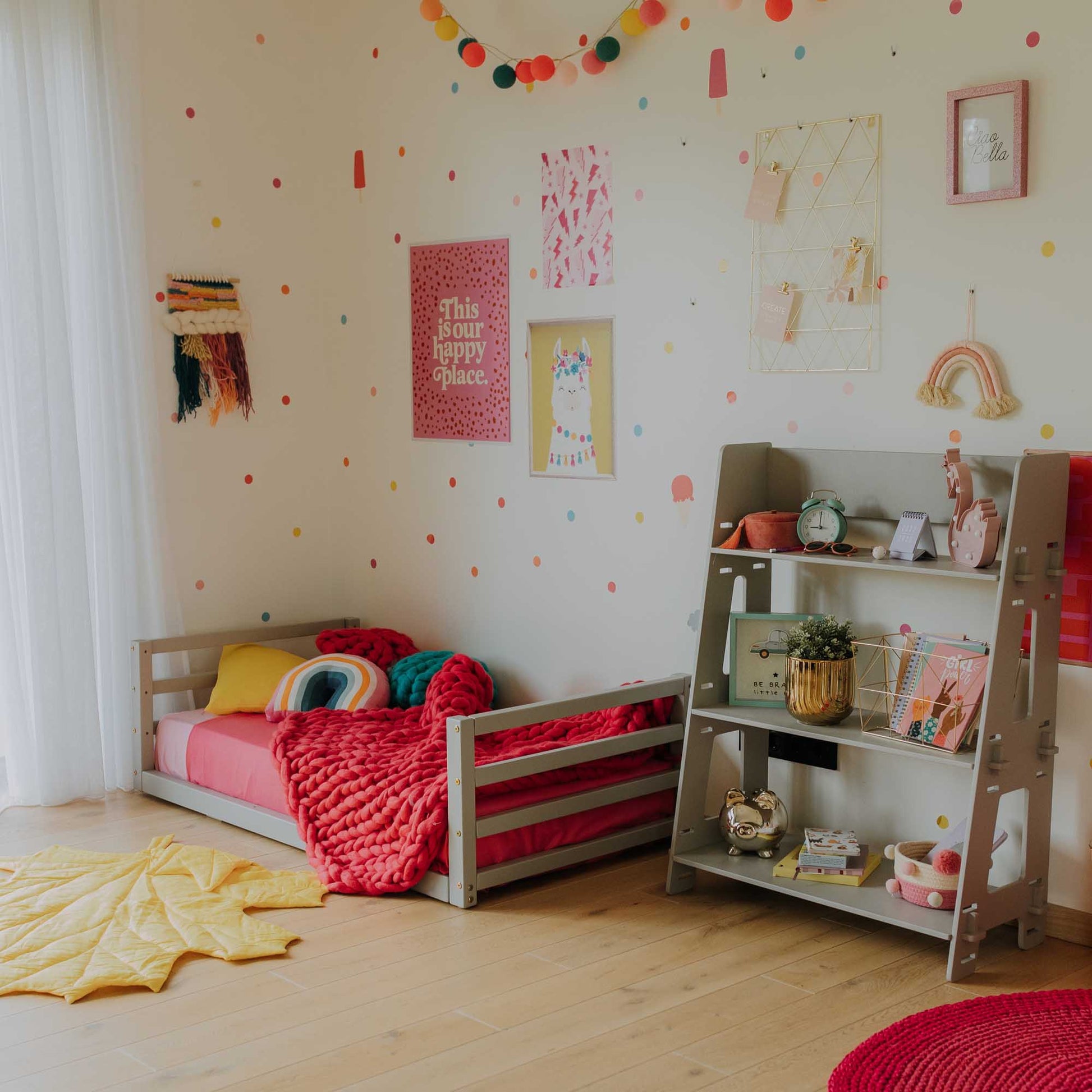 A colorful children's room with a vibrant polka dot theme and a cozy Sweet Home From Wood Toddler floor bed with a horizontal rail headboard and footboard.