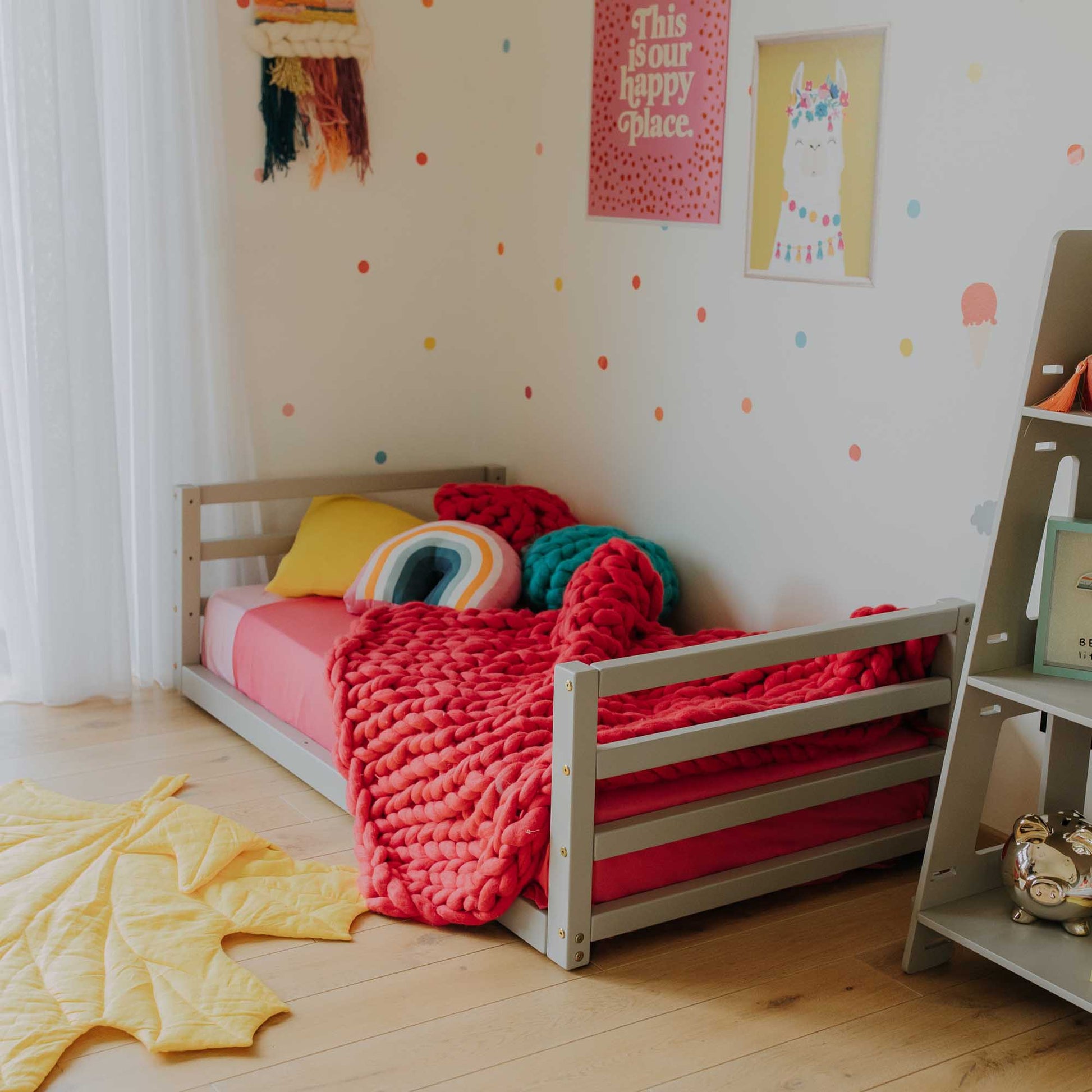 A Toddler floor bed with a horizontal rail headboard and footboard from Sweet Home From Wood in a child's room.
