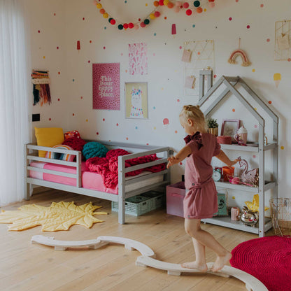 A girl's room with a Sweet Home From Wood kids' bed on legs with a horizontal rail fence and a train track.