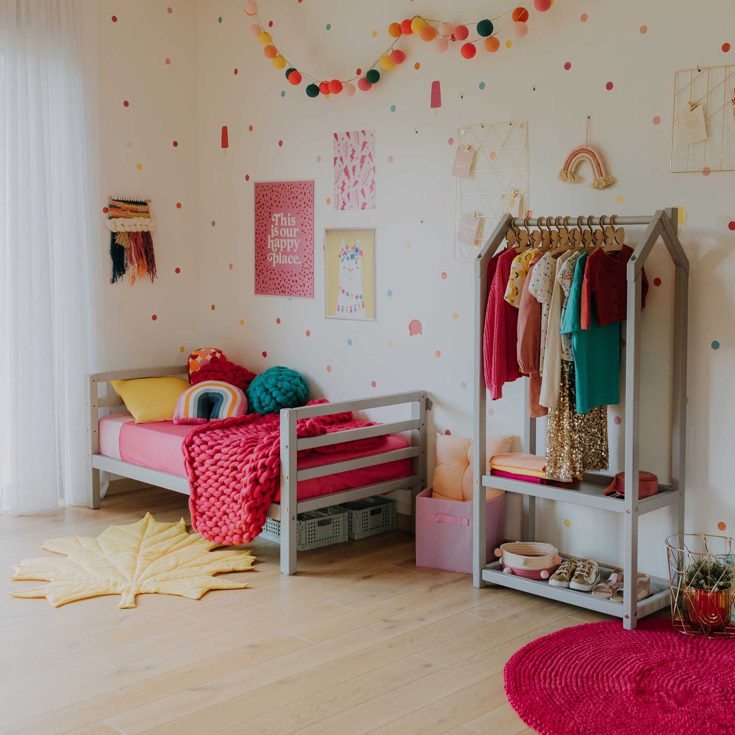A long-lasting Sweet Home From Wood 2-in-1 kids' bed with a horizontal rail headboard and footboard in a girl's room with polka dots that grows with the child.