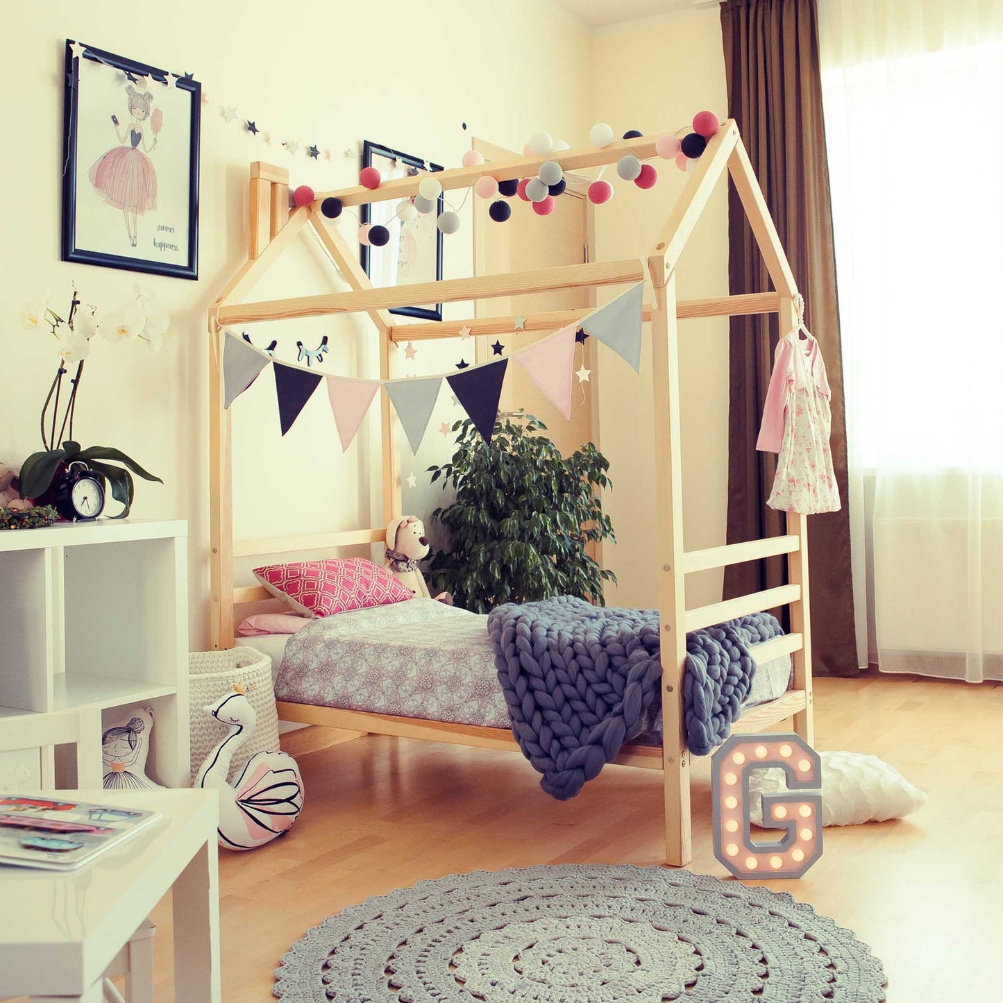 A child's bedroom with a Kids' house bed on legs with a headboard and footboard and a rug.