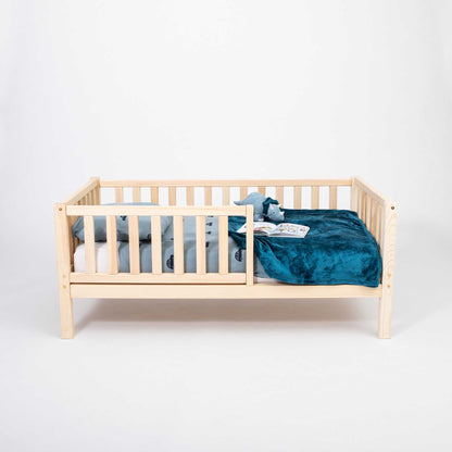 A long-lasting Sweet Home From Wood 2-in-1 toddler bed on legs with a vertical rail fence, with a blue blanket.