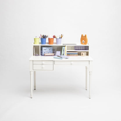 A versatile white children's Pedestal desk with open drawers, organized with school supplies, books, a calendar, and colorful containers.