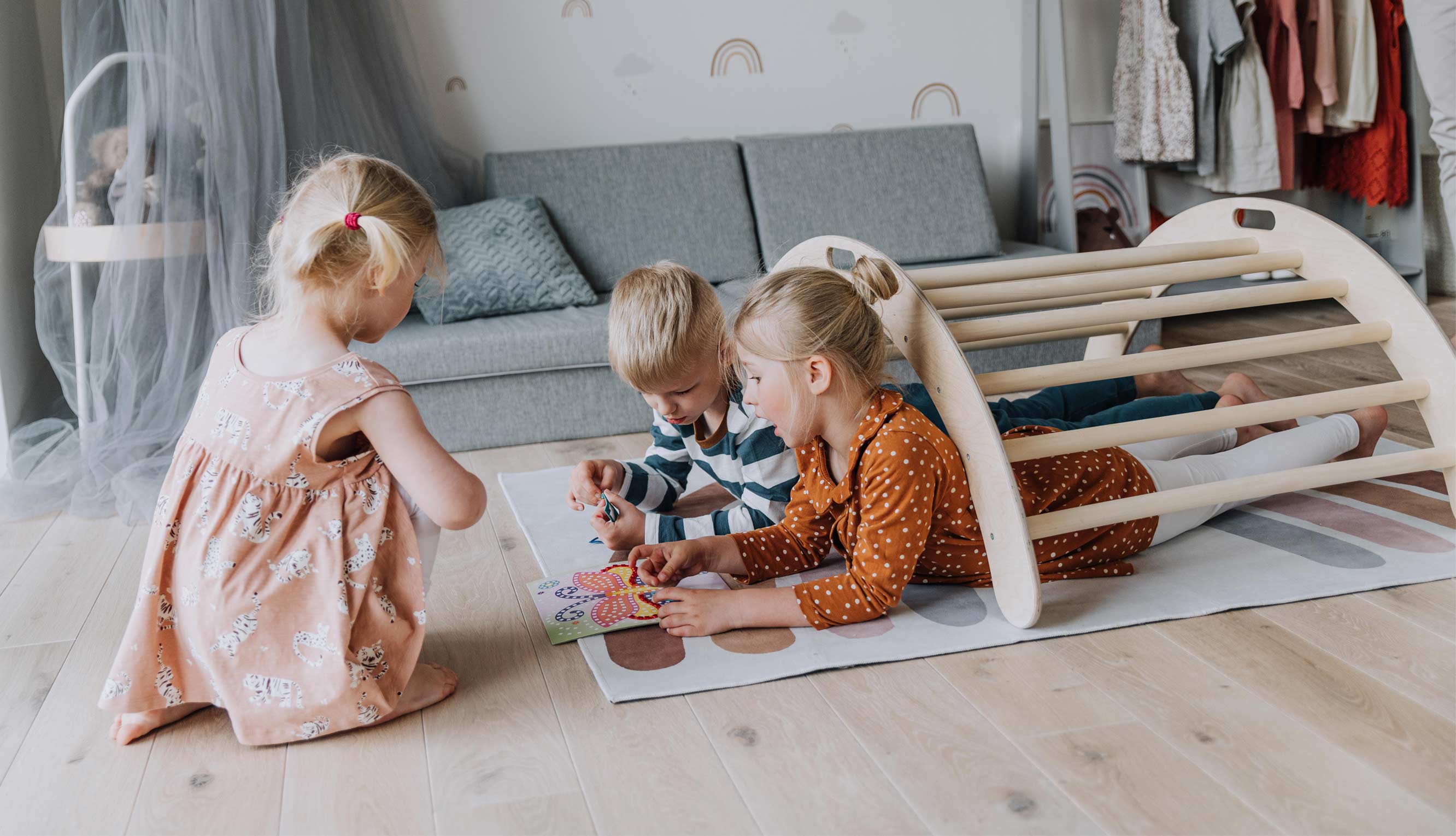 Two children playing with a wooden play structure in a living room.