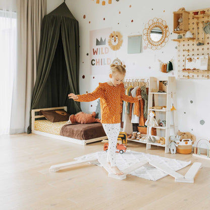 A little girl is playing in her room with her Sweet Home From Wood Balance Beam Set and climbing arch.