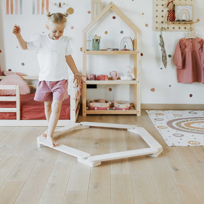 A little girl standing on a wooden floor in the Sweet Home From Wood Balance Beam Set indoor climber playroom.