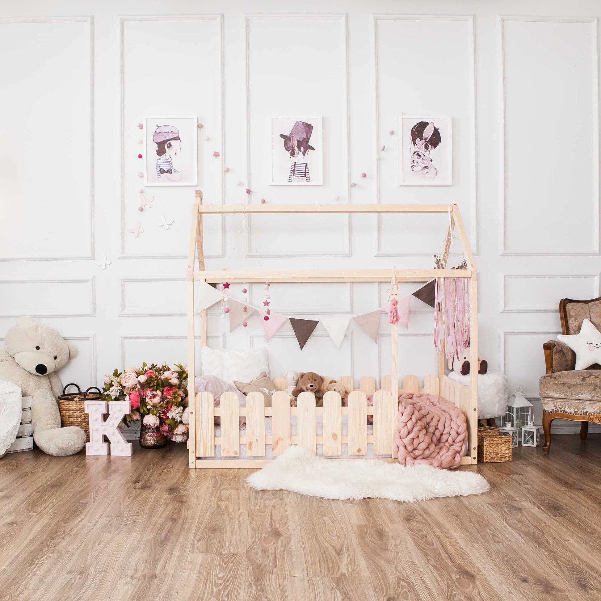A girl's room with a platform house bed featuring a picket fence and a teddy bear.