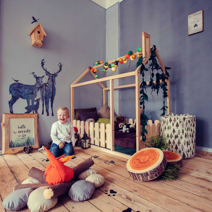 A child's room with a platform house bed with a picket fence made of wood.