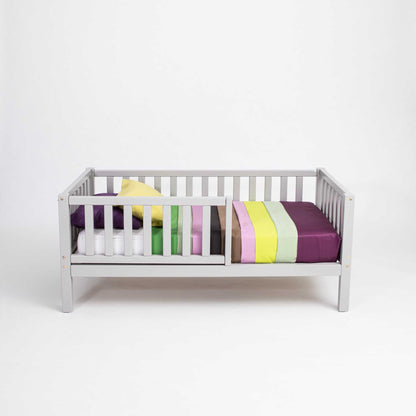 A long-lasting 2-in-1 toddler bed on legs with a vertical rail fence made of solid pine, with colorful slats from Sweet Home From Wood.