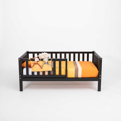 A 2-in-1 toddler bed on legs with a vertical rail fence from Sweet Home From Wood, with a long-lasting orange striped blanket.