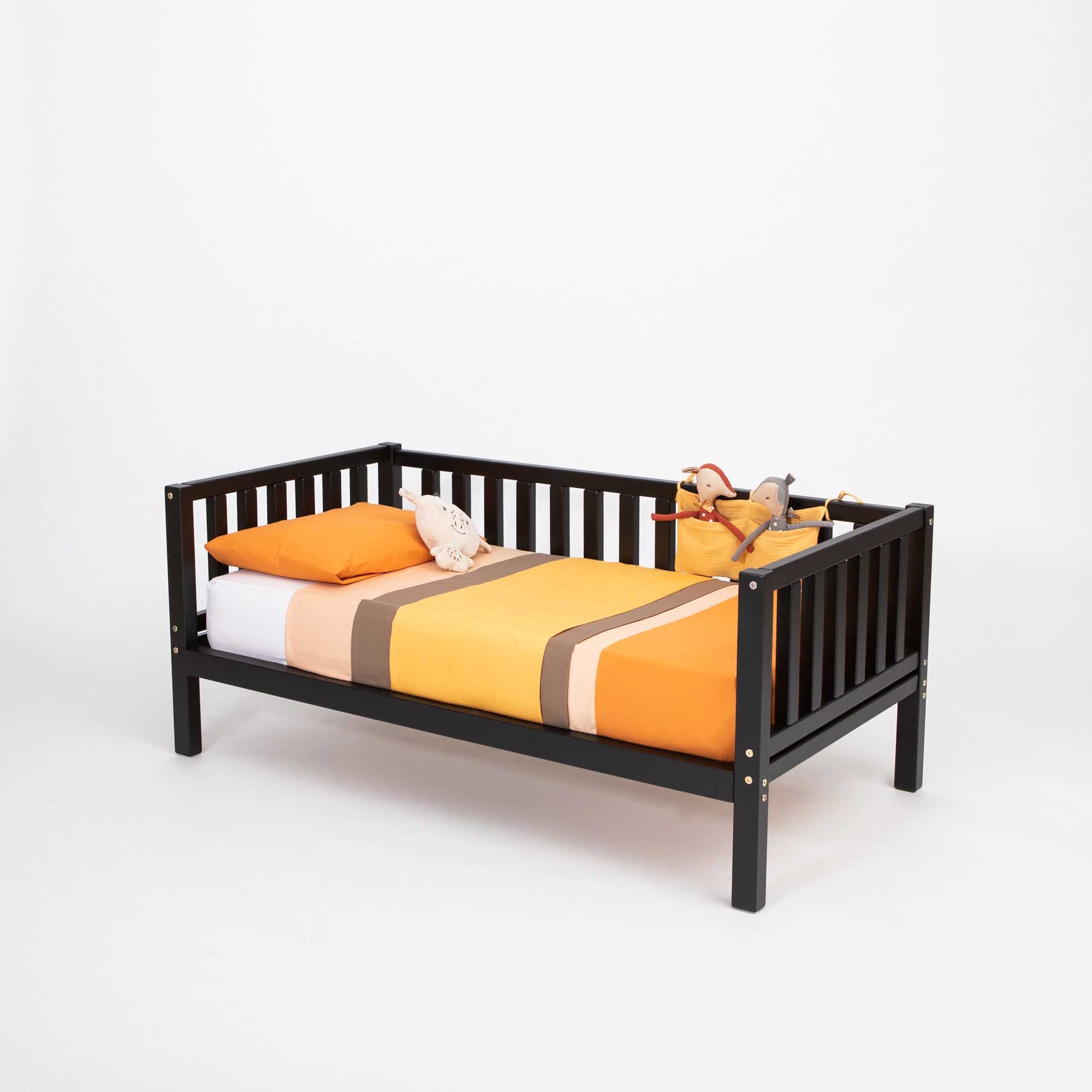 A Kids' platform bed on legs with 3-sided rails, inspired by Montessori and made by Sweet Home From Wood, with an orange and yellow blanket.