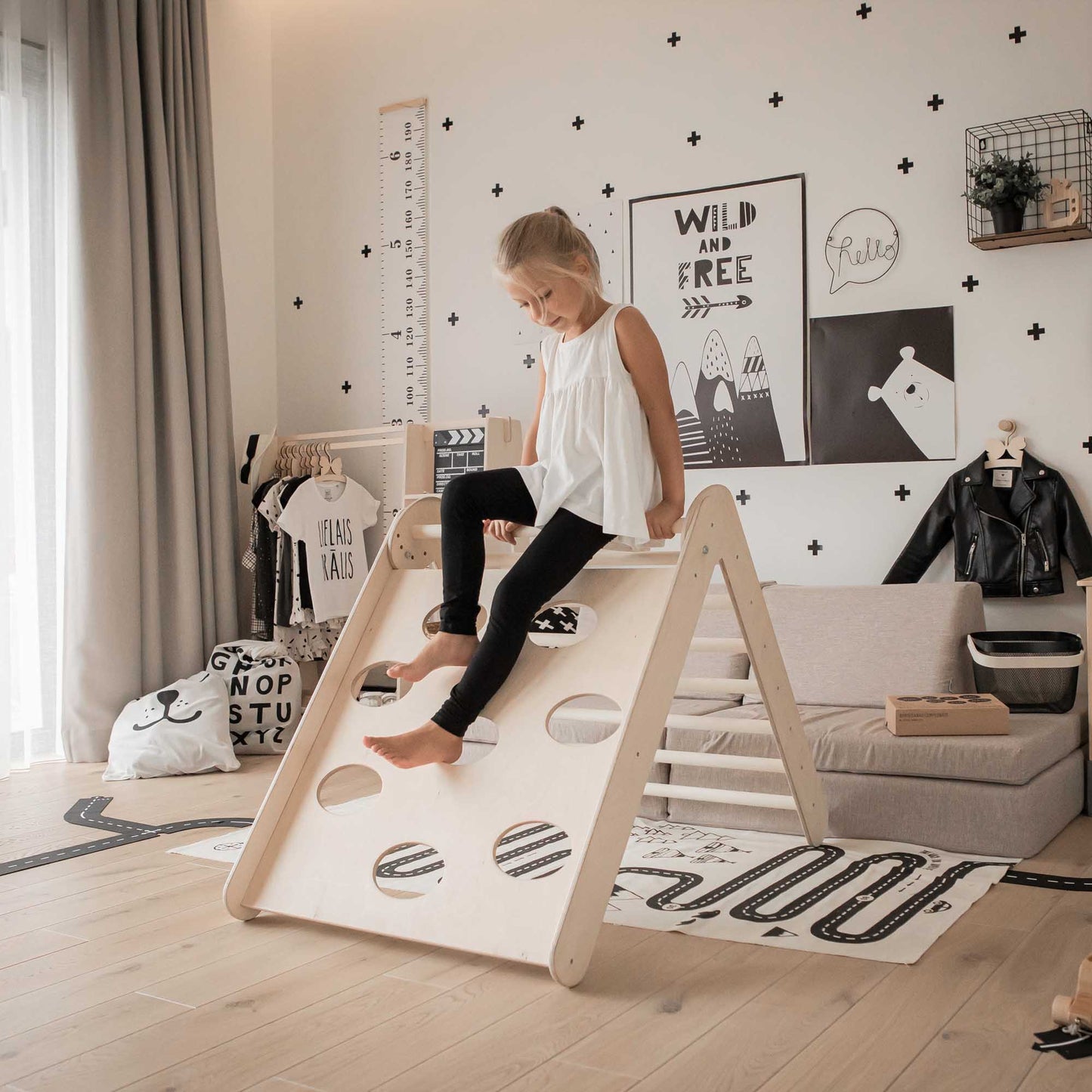 A little girl is joyfully climbing on a Transformable triangle + climbing cube / table and chair  + a ramp in a room filled with climbing toys.