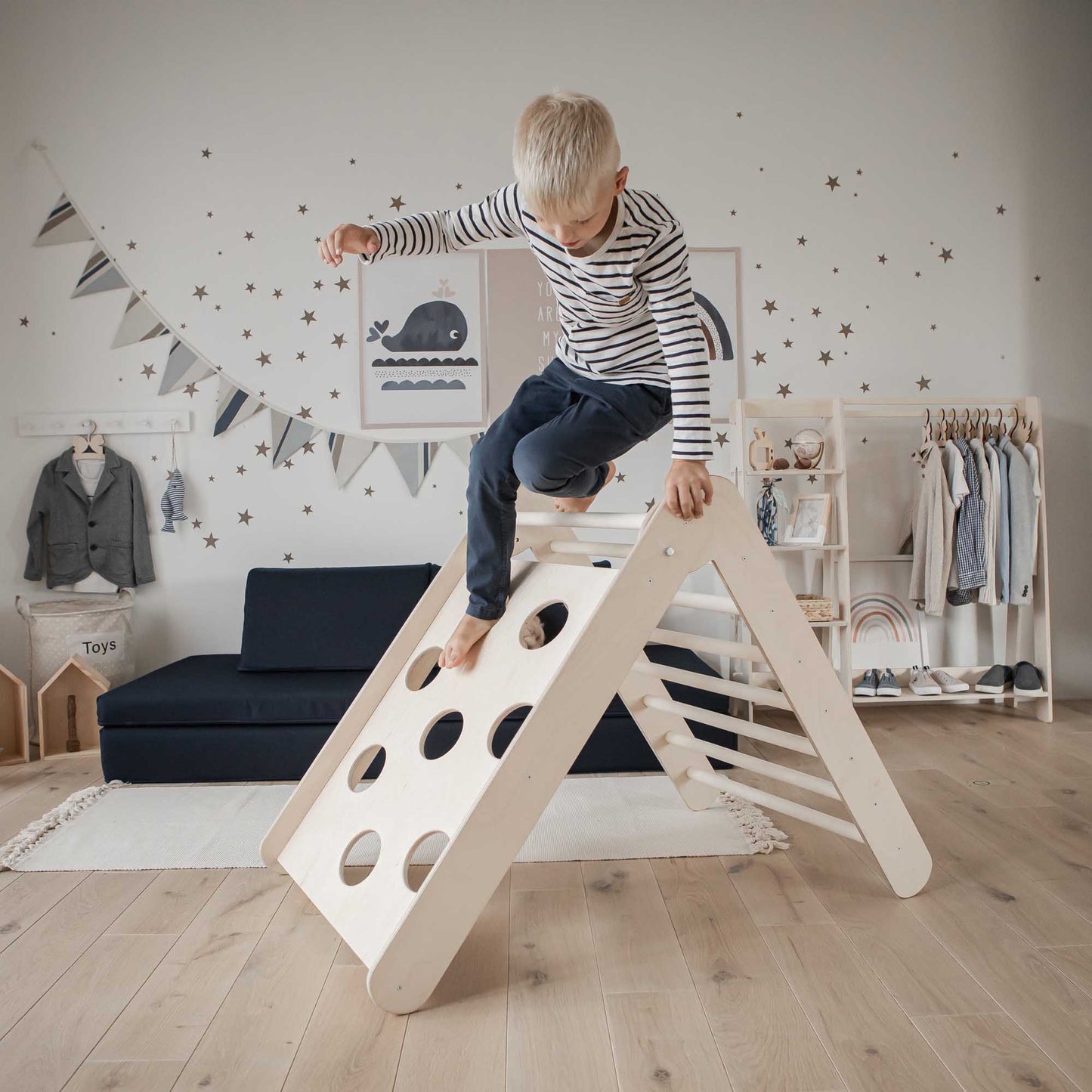 A boy is playing with a Transformable climbing triangle with 2 sensory panels in his room.