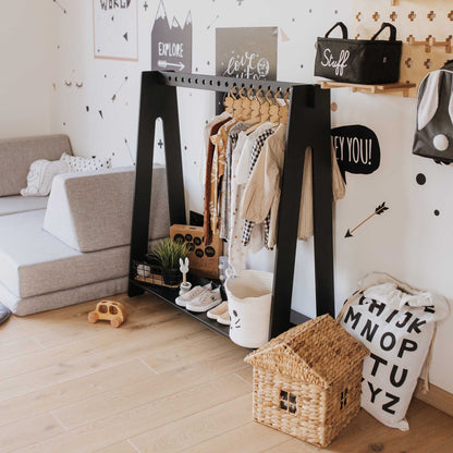 A child's room with a trendy black and white decor features a stylish A-frame kids' clothing rack from Sweet Home From Wood for easy organization.