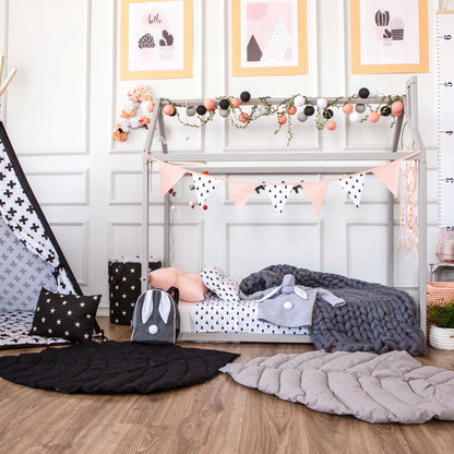 A cozy black and white nursery with a Sweet Home From Wood house-frame bed with a headboard and polka dots.