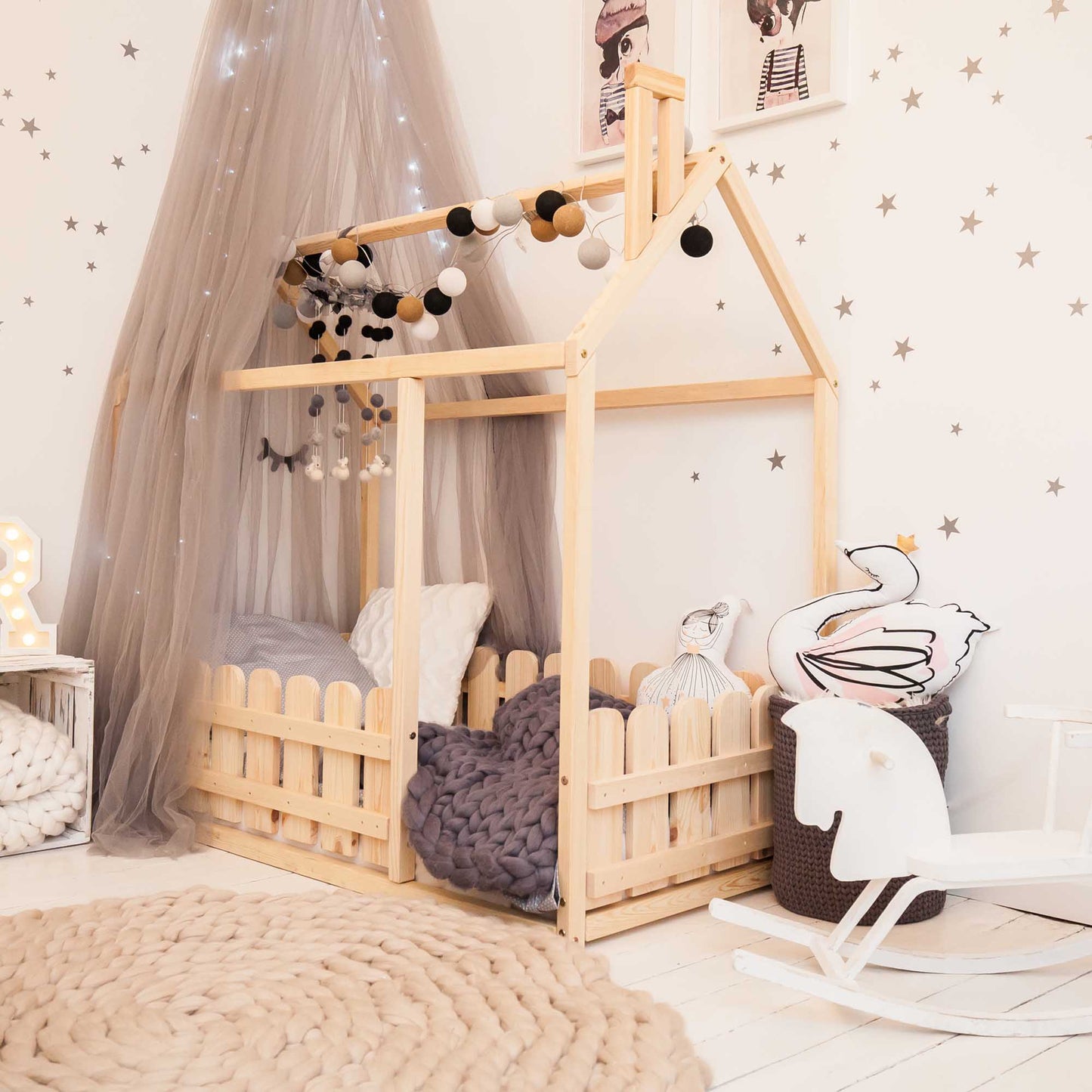 A children's room with a Platform house bed with a picket fence and a rocking chair.