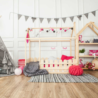 A girl's bedroom with a teepee and a platform house bed with a picket fence.