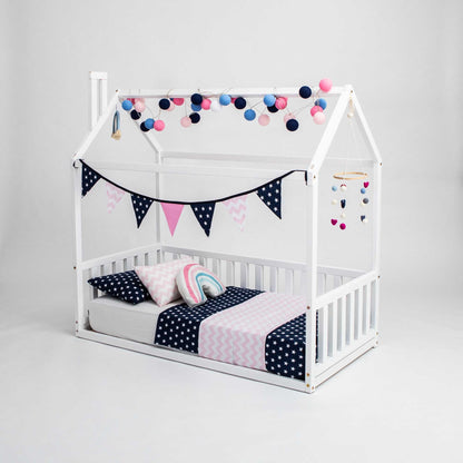 A cozy sleep haven with a white Sweet Home From Wood Montessori house bed adorned with polka dot pillows and bunting.