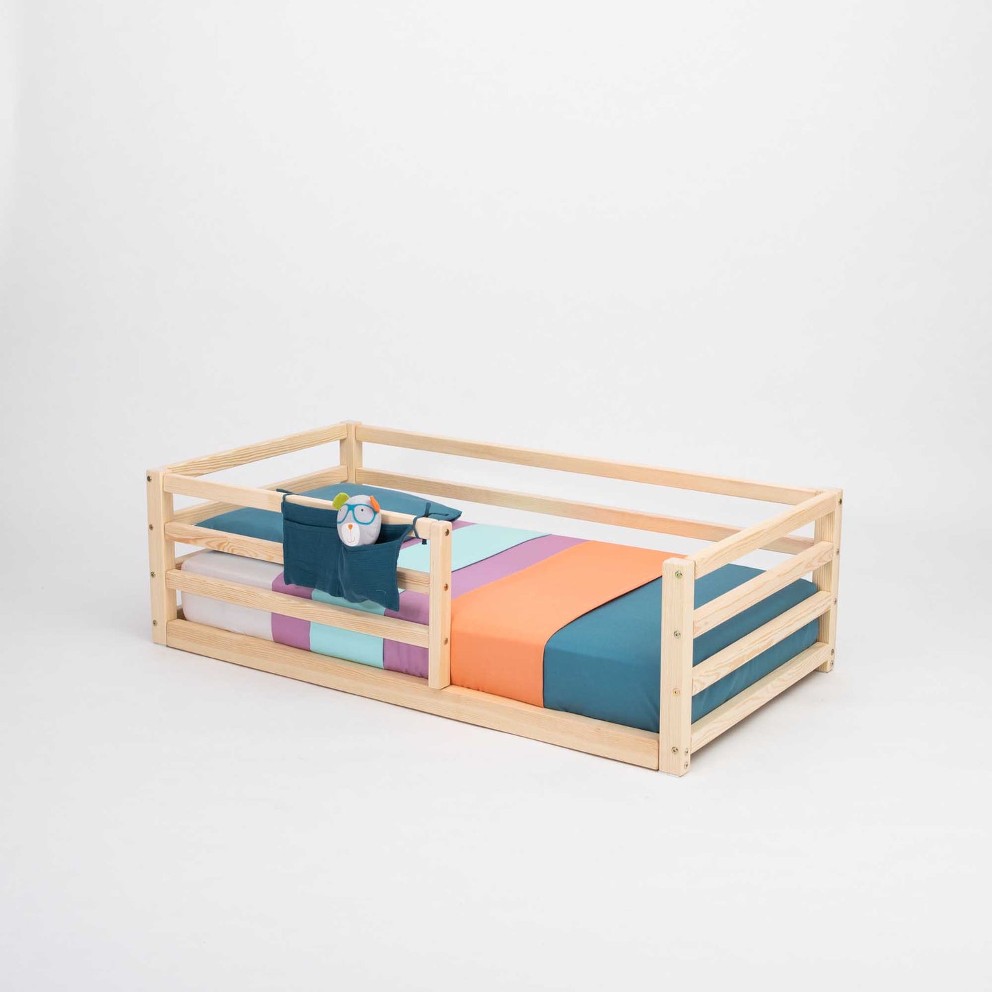 A Sweet Home From Wood 2-in-1 transformable kids' bed with a horizontal rail fence and a colorful striped sheet.