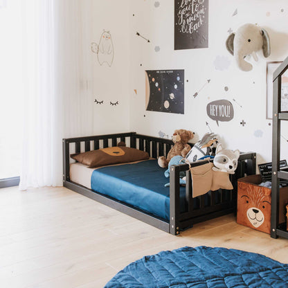 A boy's room with a solid pine or birch wood bed featuring a Sweet Home From Wood 2-in-1 toddler bed on legs with a 3-sided vertical rail design, paired with a cozy blue rug.