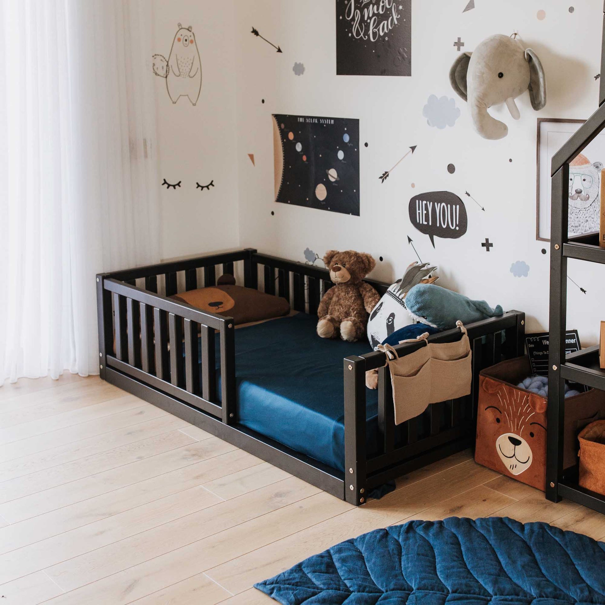 A long-lasting Sweet Home From Wood children's room with teddy bears and stuffed animals, featuring a 2-in-1 toddler bed on legs with a vertical rail fence.