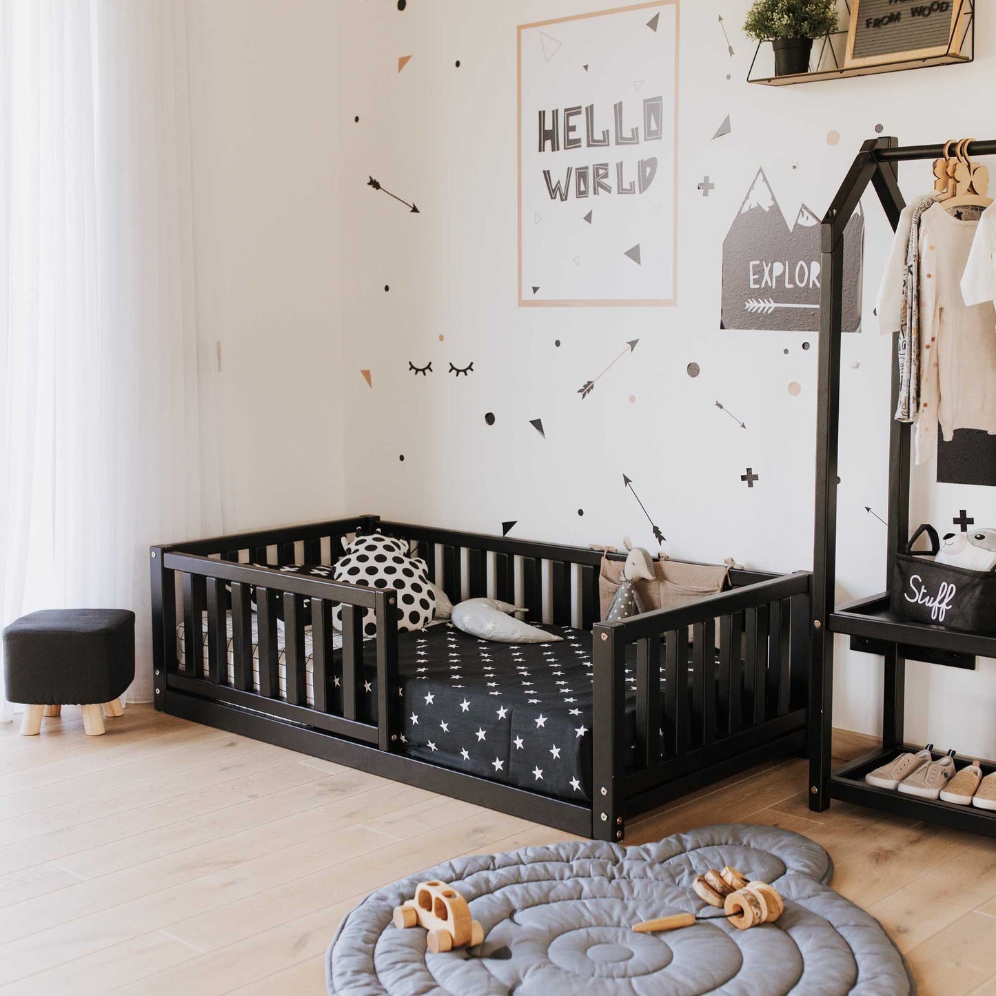 A child's room with a Sweet Home From Wood Montessori kids' bed with a fence and polka dot wall decals, providing independent sleeping and security.