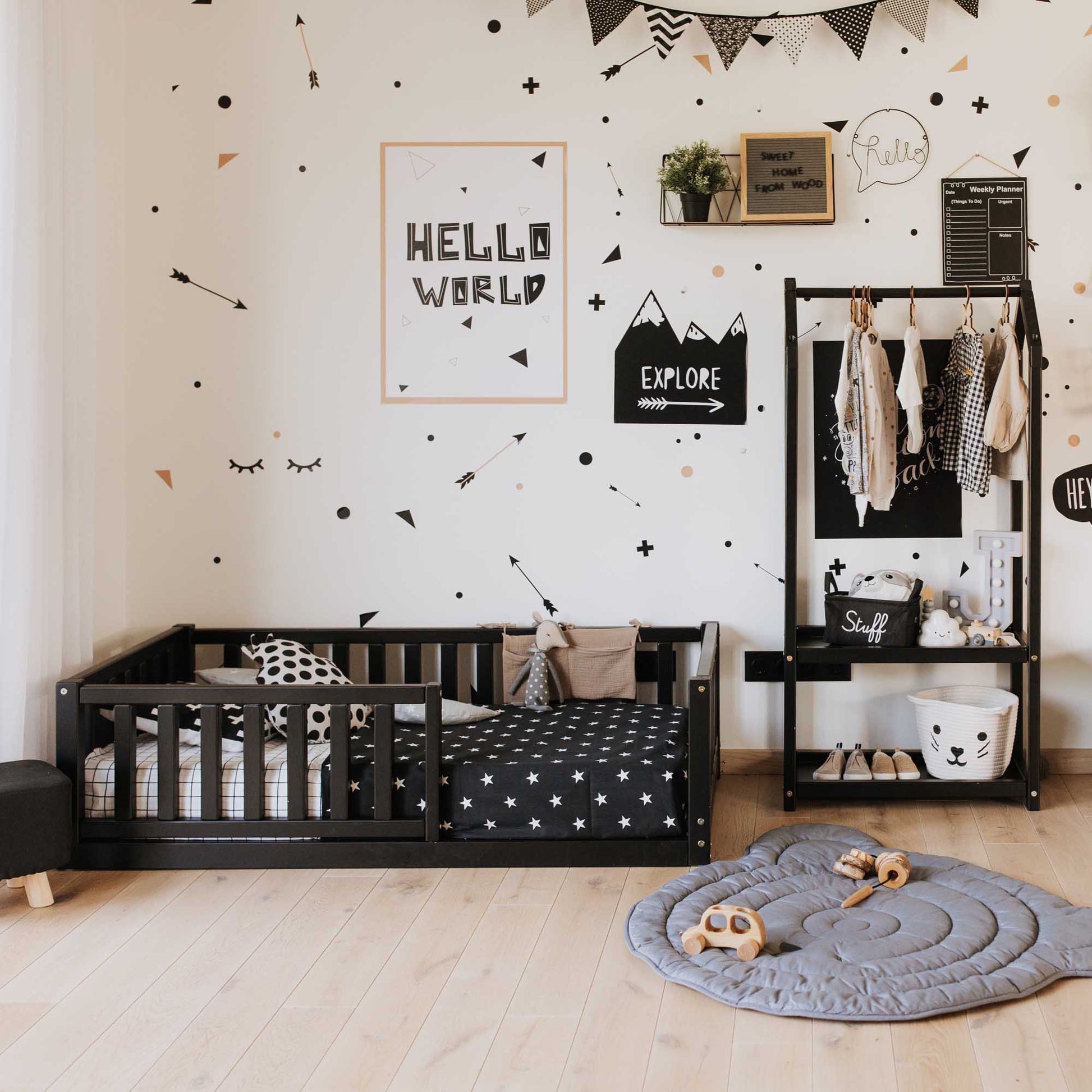 A child's room with black and white decor featuring a Sweet Home From Wood Montessori kids' bed with a fence and polka dot accents. Ideal for fostering a sense of security and promoting independent sleeping.