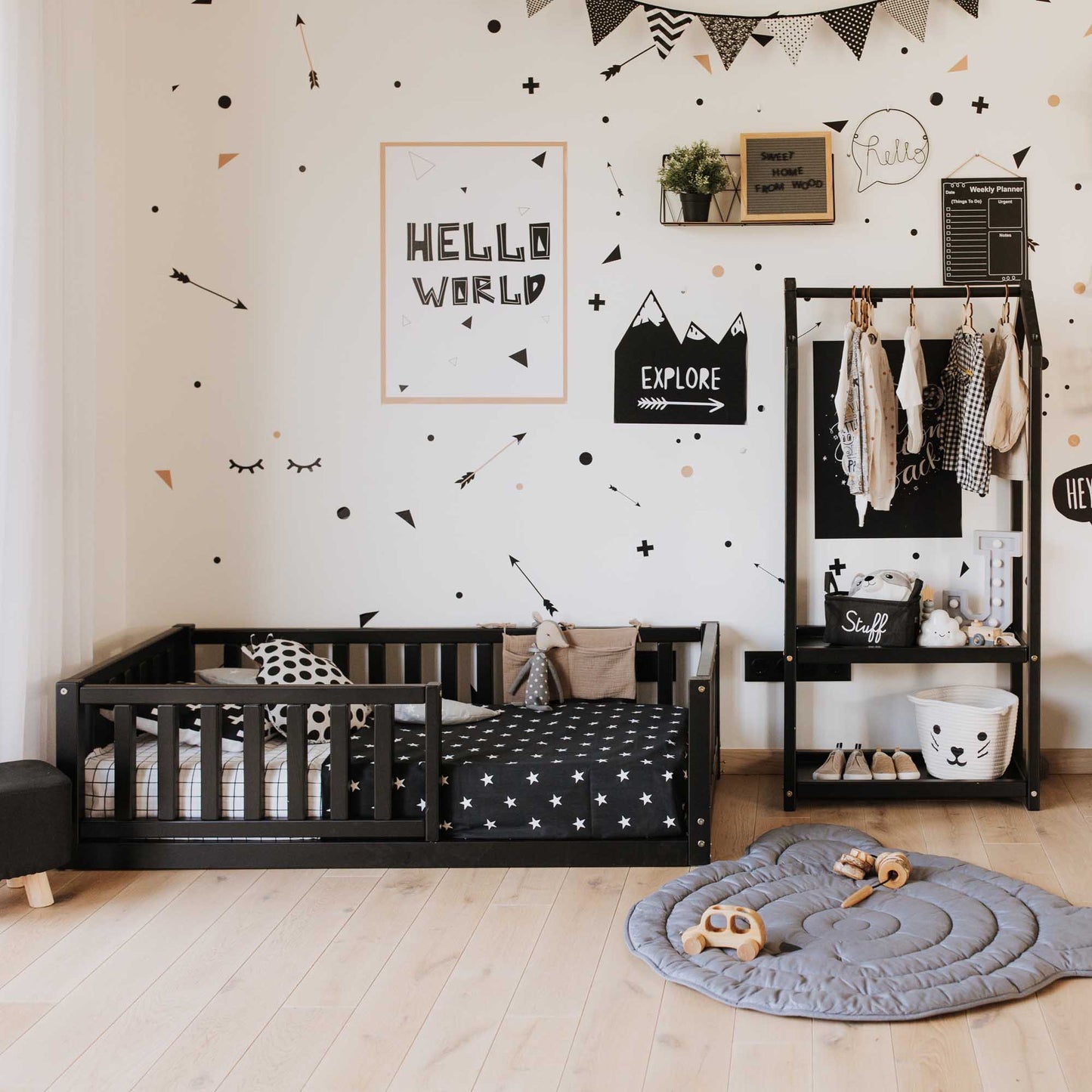 A child's room with the Sweet Home From Wood 2-in-1 toddler bed on legs with a vertical rail fence, featuring black and white decor with polka dots.