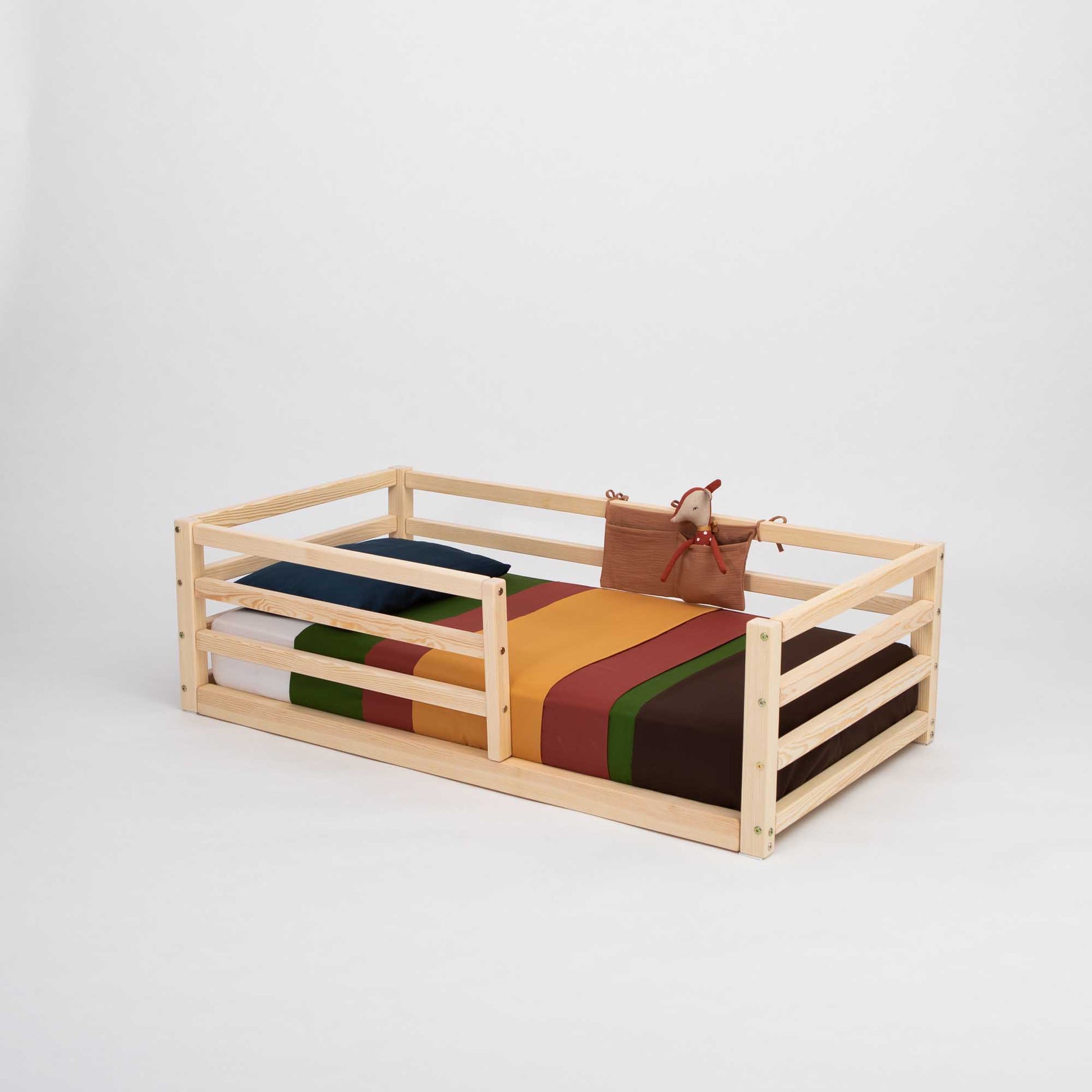 A colorful striped blanket adorns a child's Sweet Home From Wood 2-in-1 transformable kids' bed with a horizontal rail fence made of wood.