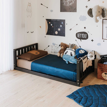 A children's room with a 2-in-1 kid's bed on legs with a vertical rail headboard and footboard, toys, and wall decals.