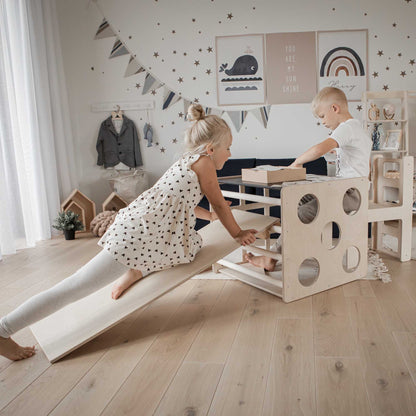 Two children playing with a transformable climbing cube / table and chair + ramp in a room.
