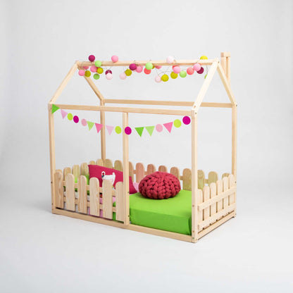 A platform house bed with a picket fence and pom poms.