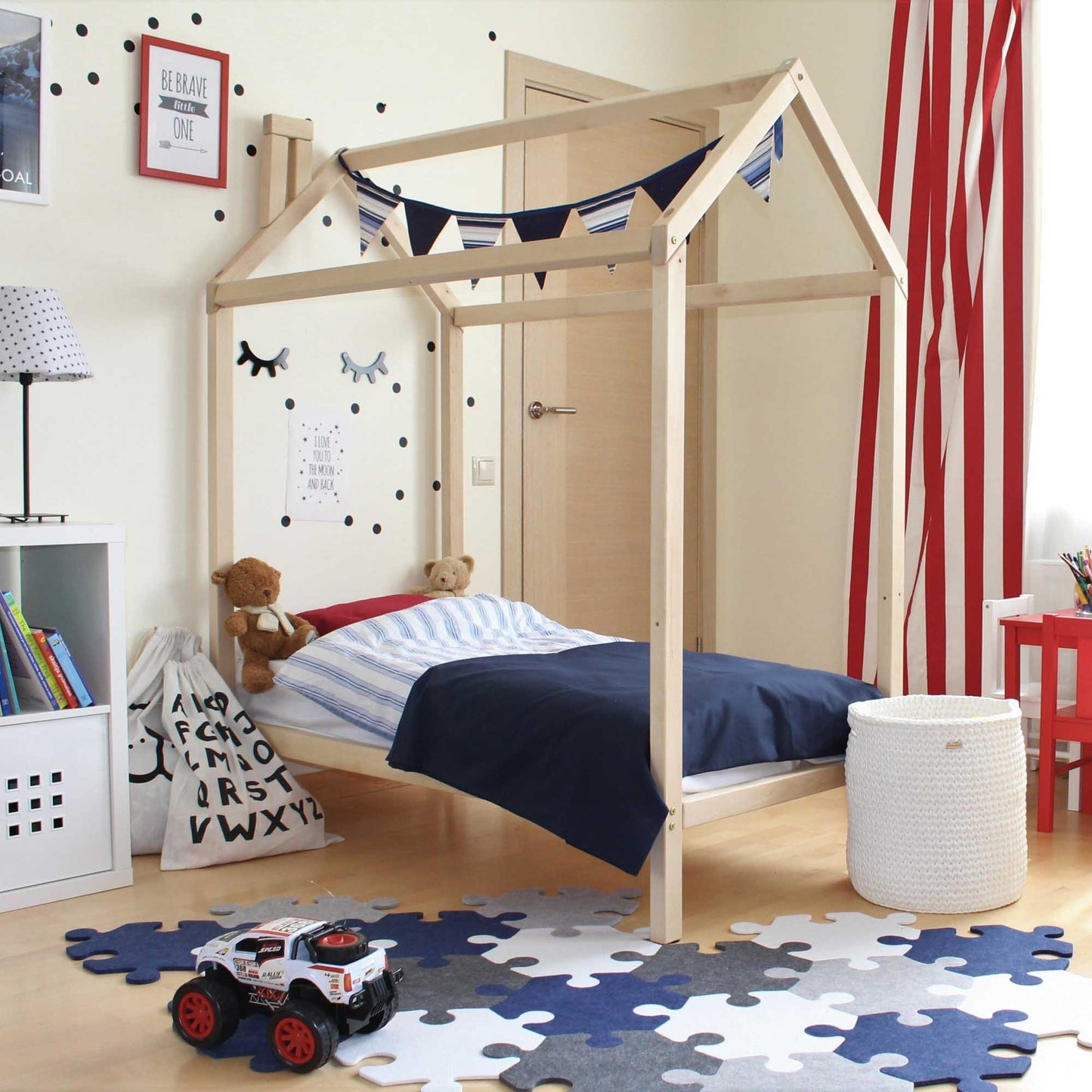 A child's room with a wooden house bed on legs and a rug.