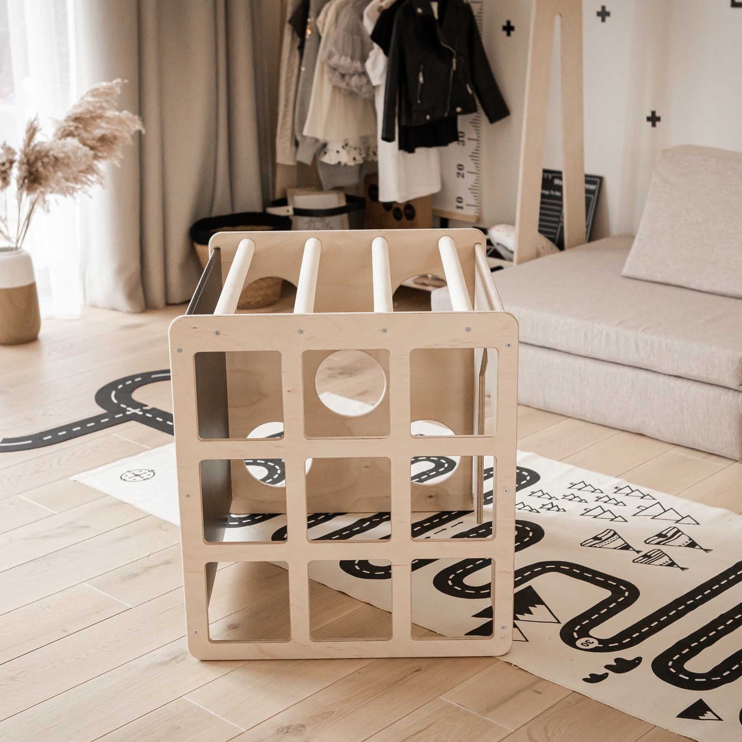 A child's room with a Sweet Home From Wood activity cube with sensory panels and a ramp on the floor and a balance beam.