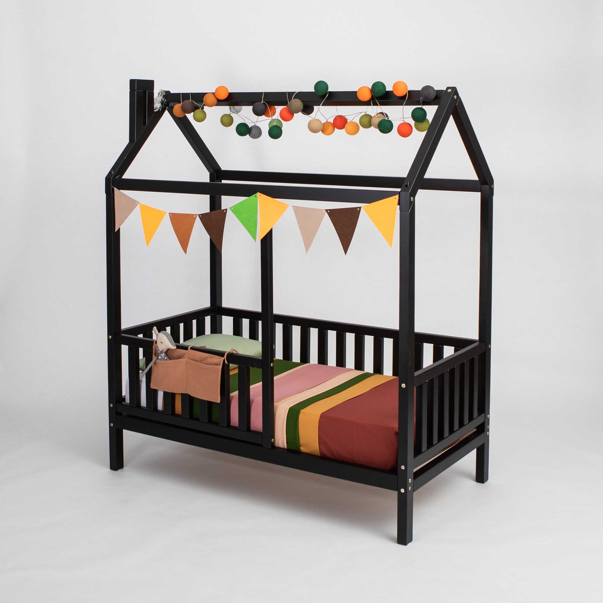 A black Kids' house bed on legs with a fence, with a canopy and bunting.